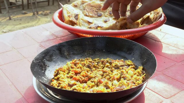 At a charming local dhaba, people relish a delightful breakfast featuring warm, crispy parathas served alongside a flavorful omelet.