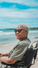 Fototapeta premium Elderly woman enjoying a peaceful moment on a sandy beach, standing with eyes closed and face lifted towards the sky, with gentle ocean waves in the background.