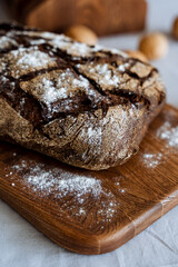 A freshly baked loaf of bread is sitting comfortably on a wooden cutting board, ready to be sliced and enjoyed by anyone who loves delicious baked goods and homecooked meals