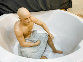 A bald mannequin is leisurely sitting in a bathtub, comfortably wrapped in a fluffy towel, adding a unique touch to the scene, evoking a sense of relaxation and tranquility