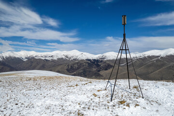 The triangulation point on Mariam summit and Pambak Range cowered with snow on sunny spring day....