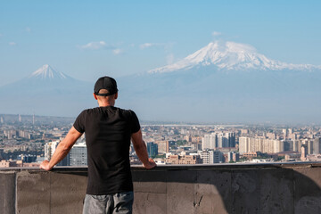 A tourist (in focus) looking at Yerevan and Mount Ararat (out of focus) from Cascade Complex view point. Armenia.