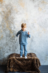 A young boy is joyfully standing on a vibrant pile of colorful blankets, fully immersed in a world...