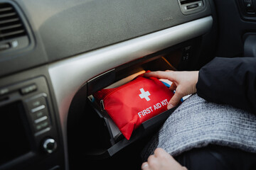 A person is retrieving a first aid kit from the glove compartment located inside the glove box of...