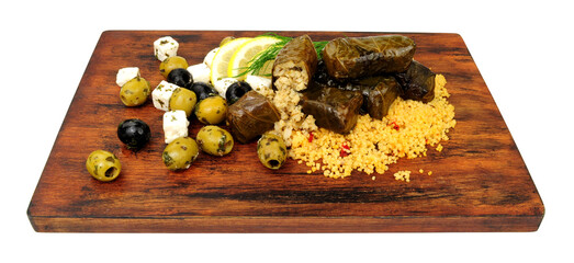 Rice stuffed vine leaves meal with couscous, Greek feta cheese and black olives on a wooden serving board isolated on a white background