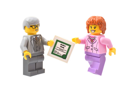 Lego minifigure of businessmen or chef with aword certificate and smiling employee. Editorial illustrative image of popular plastic toy constructor.