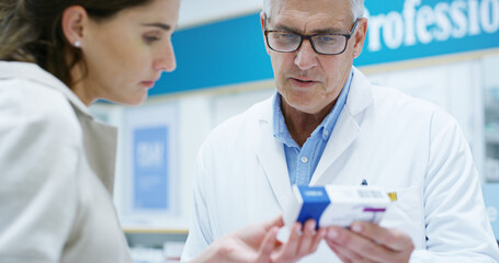 Pharmacist, woman and man with box, medicine and helping hand with reading for benefits, info or side effects. People, pills or drugs with advice, consulting and healthcare with supplements at store