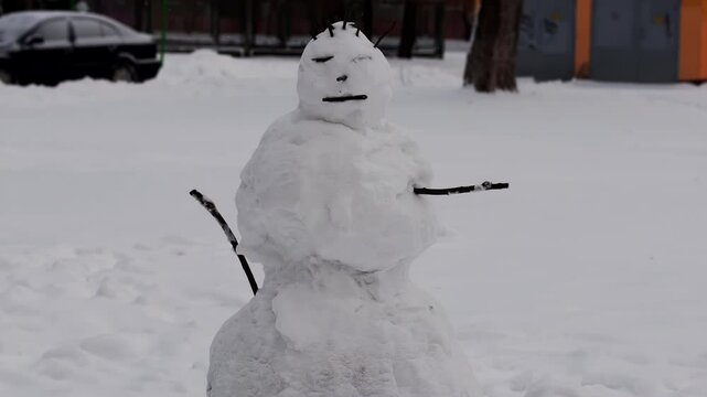 A snowman stands in the yard in the snowy winter, slow motion