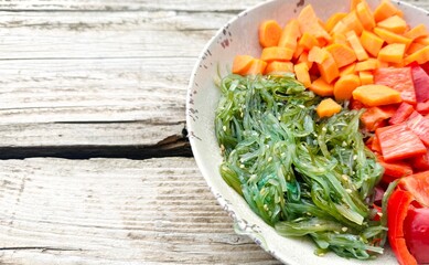Bowl with seaweed and chopped vegetables. Preparation of vegetarian poke bowl. Asian food.