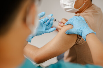 Close-up of a doctor's hand wearing blue gloves carefully injecting a vaccine, conveying the importance of health and care in a detailed and professional manner.