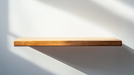 Wooden shelf positioned against a white background with gentle shadows. The wooden shelf is illuminated by natural light, ideal for product presentation with ample copy space.