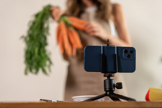 Content creator filming smartphone recipe fresh vegetables carrots healthy food vlog social video recording tripod