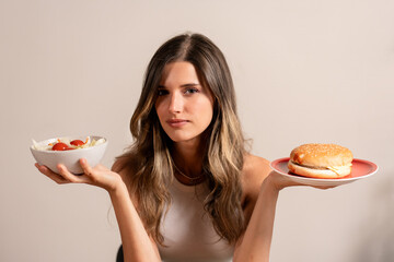 Young woman choosing between healthy salad unhealthy burger diet choice lifestyle wellness...