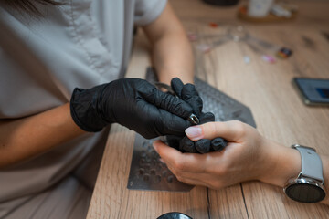 Manicure master sharpens nails on the wooden table