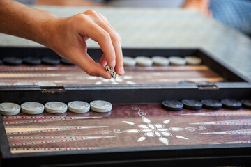 Hand rolling dice in traditional backgammon game close-up
