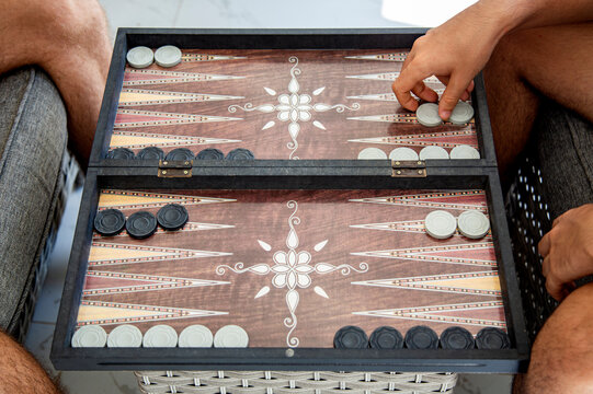 Two persons playing backgammon game close-up