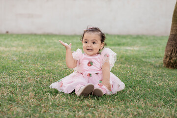 A little girl sitting on the ground with her hand up