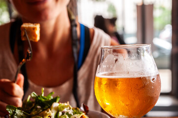 Close up of a glass of beer with a blurred woman in the background.