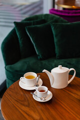 Tea set with honey on a rounded wooden table and green couch