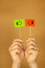 Vertical image of male hand holding two flags with like and dislike symbols on red and green papers...