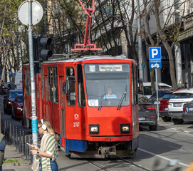 Fototapeta premium Red train with the number 257 on it is driving down a street