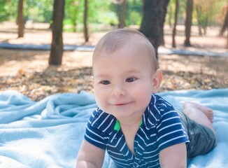 Smiling baby crawling in a park. About 8 months.