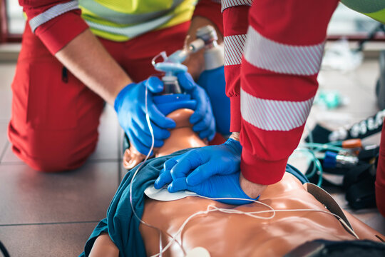 Hands of paramedic and doctor during resuscitation. Team of emergency medical service during CPR training on dummy. Themes rescue, urgency and health care.