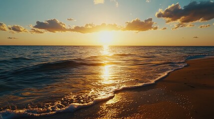 Fototapeta premium Golden sunset over the calm ocean with gentle waves and sandy beach.