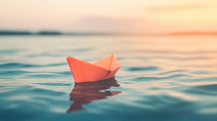 A small, colorful paper boat glides effortlessly across the smooth ocean surface as the sun sets in the background