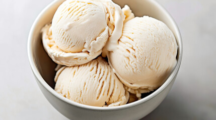 Close-up of three scoops of vanilla ice cream in a white bowl on a light background.
