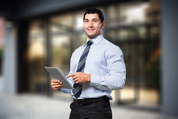 Young businessman posing outdoor at office building with digital tablet