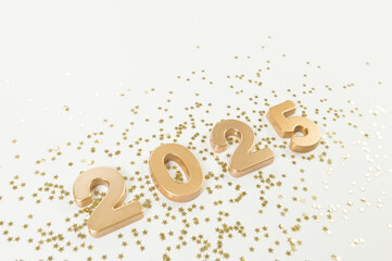 2025 Happy New Year. Top view of gold numbers, gold stars confetti on white background. Copy space, flat lay.