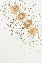 2026 Happy New Year. Top view of gold numbers, gold stars confetti on white background. Copy space, flat lay.
