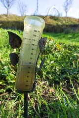 In full rain gauge in a sunny garden. After rain comes sunshine.    