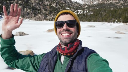 Young man on a video call using cell phone to share winter mountain vacations on social media