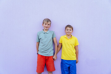 Two young boys standing against a colorful purple wall