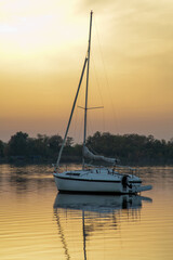 A serene sailboat floats on a calm lake at sunset, embodying relaxation and wanderlust during the...
