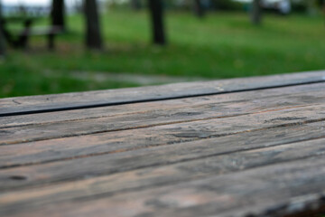 A close-up of an empty wooden picnic table in a serene park setting, evoking the concept of outdoor relaxation and leisure activities