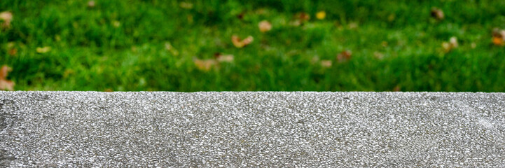 Close-up of a textured concrete surface with blurred green grass background, representing urban greenery and environmental sustainability