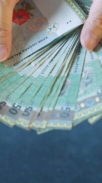 Person is counting a stack of fifty ringgit bills