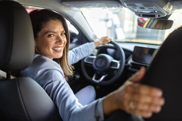 Happy young woman testing new car before buying in showroom salon, concept buy first vehicle.. Test...