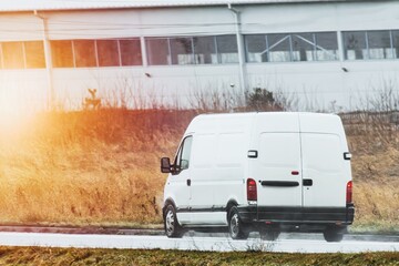 Fast white van on rural road with green scenery