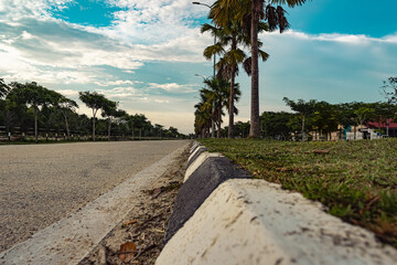 Obraz premium Beautiful view of depth of rural road with space in middle. Most beautiful road in broad daylights, trees, blue sky in spring with nature background in Malaysia