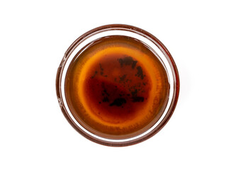 Used cooking oil old  from frying in a small cracked glass cup isolated on white background. should not be reused because that may contain residues many carcinogens cause of cancer and other diseases.