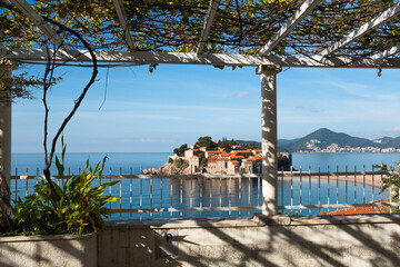 Scenic View of Saint Stefan Island in the Adriatic Sea from a Pergola. The island’s charming...