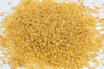 Macro scattered bulgur cracked wheat on a white background