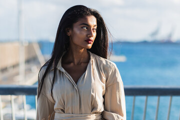 Indian businesswoman gazing out at the sea from a coastal boardwalk