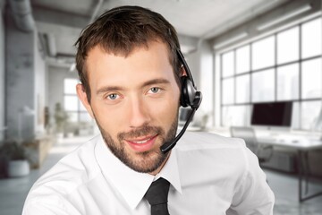 Happy call center worker wearing headset working in support office.