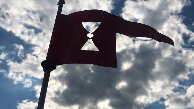 Hussite flag - a weather vane with a chalice against sky with clouds