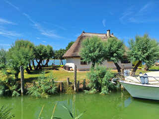 Naklejka premium The thatched roof tourist house is located next to the river with a boat.